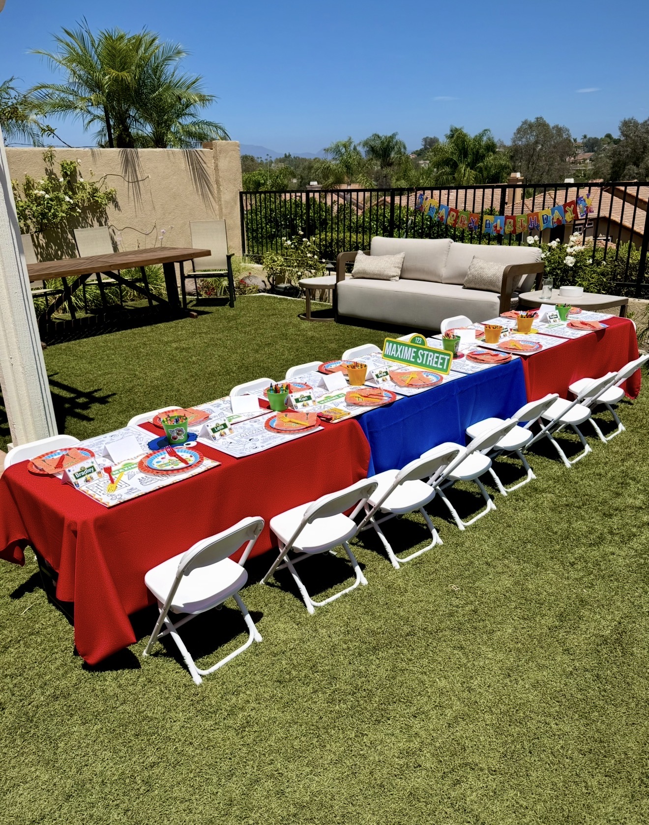 Complete Sesame Street themed kids table setup with chairs, linens, personalized place cards, coloring placemats, and crayons